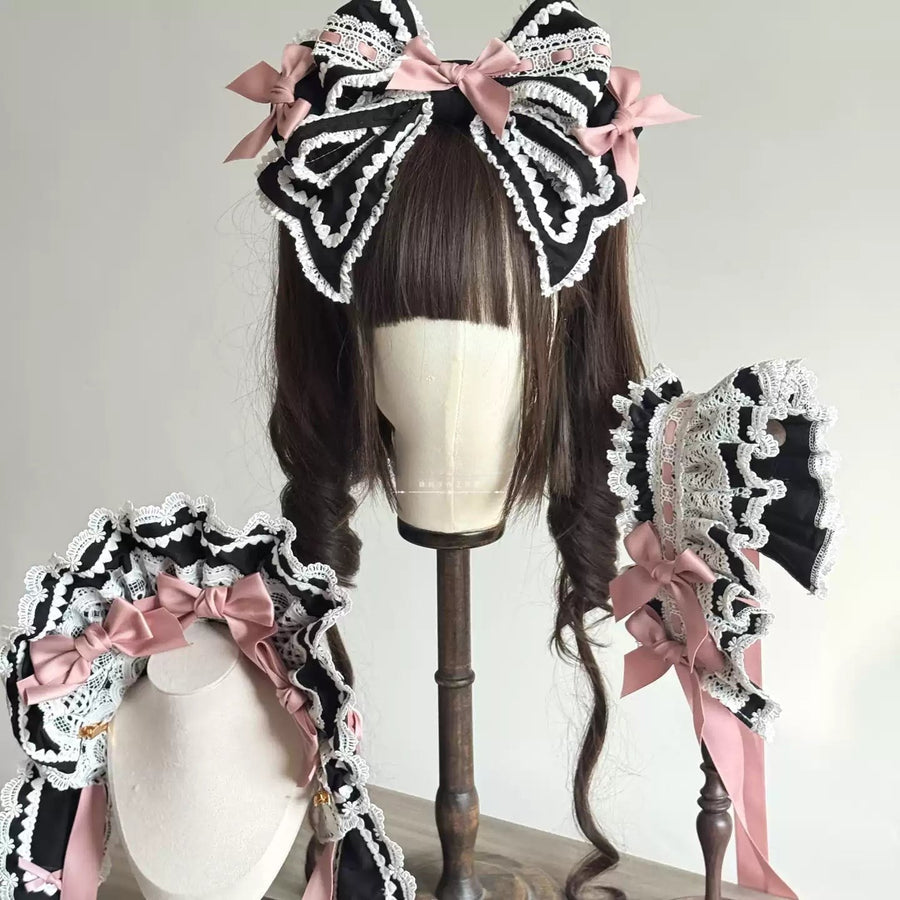 Black and white lace Lolita-style hair accessory set with pink bows, displayed on a mannequin head with long dark brown hair, plus two matching accessories on stands against a plain light background.