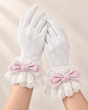 Both hands wearing lined white lace gloves with blush pink Christmas Bridal bow cuffs